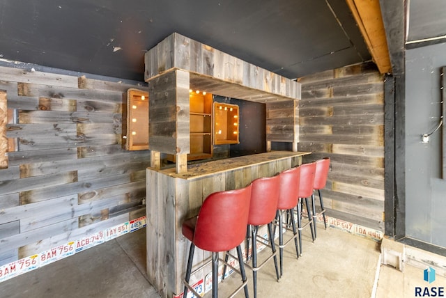 bar featuring wooden walls and concrete floors