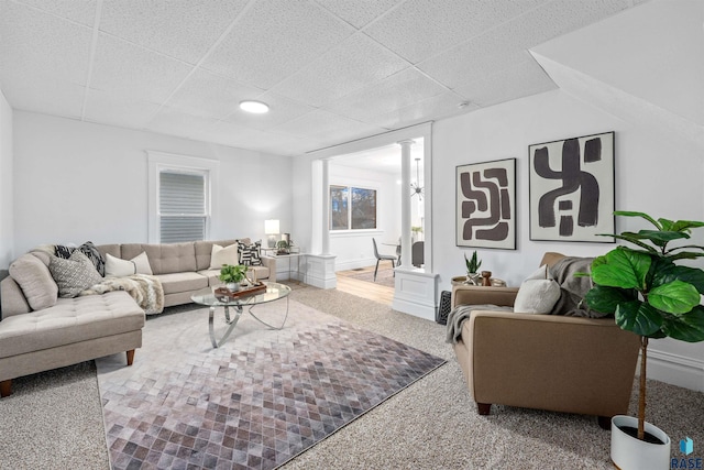 living room with ornate columns, carpet floors, and a drop ceiling