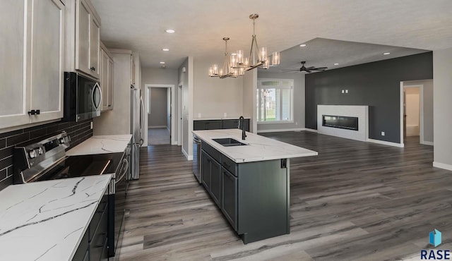 kitchen with sink, a center island with sink, appliances with stainless steel finishes, pendant lighting, and white cabinets