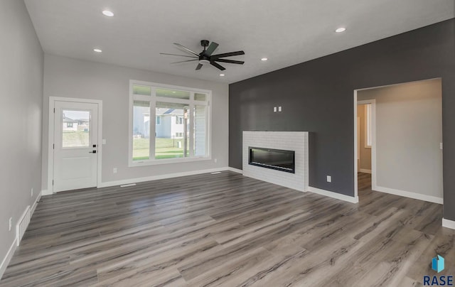 unfurnished living room with hardwood / wood-style flooring, ceiling fan, and a fireplace