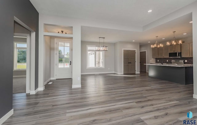 unfurnished living room with hardwood / wood-style flooring, an inviting chandelier, and a tray ceiling