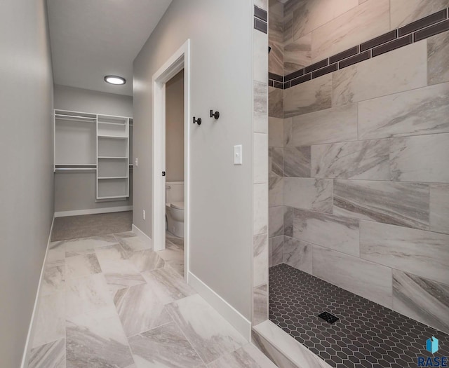 bathroom featuring a tile shower and toilet