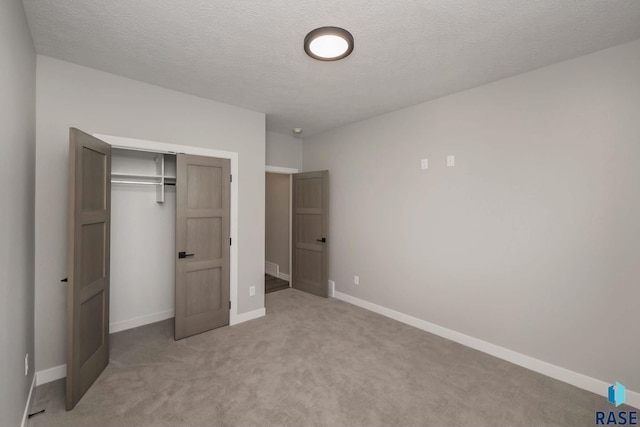 unfurnished bedroom featuring light colored carpet, a textured ceiling, and a closet