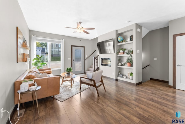 living area with dark hardwood / wood-style flooring, built in shelves, and ceiling fan