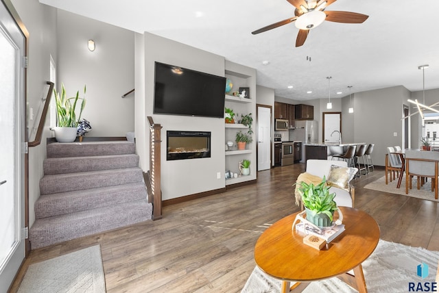 living room with dark wood-type flooring and ceiling fan with notable chandelier