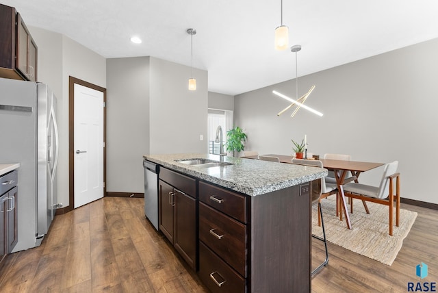 kitchen featuring pendant lighting, sink, appliances with stainless steel finishes, a kitchen breakfast bar, and an island with sink