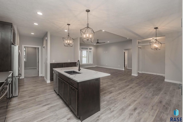 kitchen featuring stainless steel appliances, an island with sink, sink, and pendant lighting