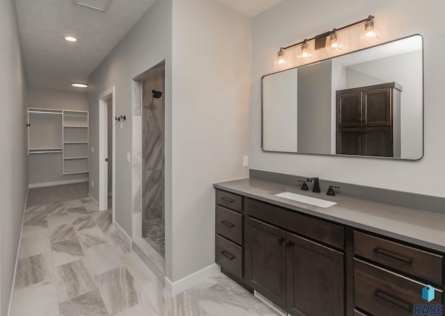 bathroom featuring vanity, tiled shower, and a textured ceiling