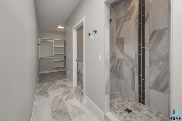 bathroom featuring tiled shower and toilet