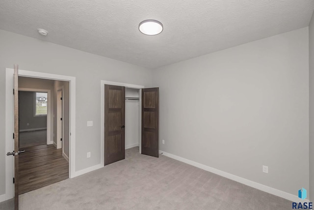 unfurnished bedroom featuring light carpet, a closet, and a textured ceiling