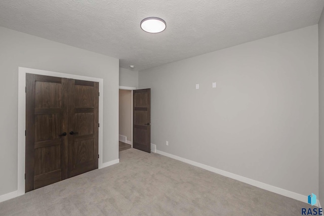 unfurnished bedroom featuring light carpet, a closet, and a textured ceiling