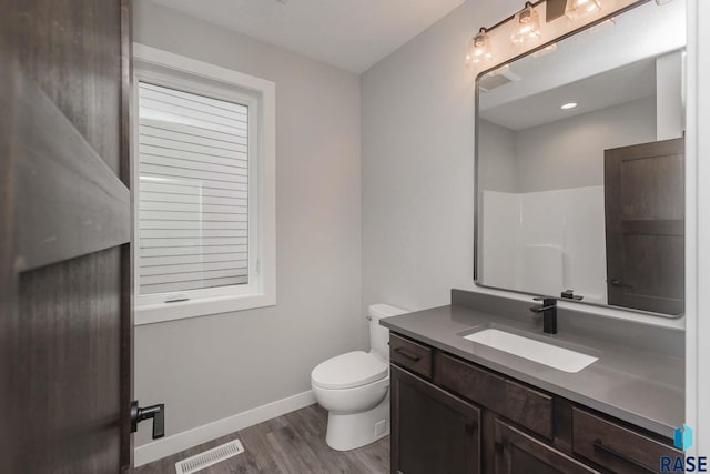 bathroom featuring hardwood / wood-style flooring, vanity, toilet, and a shower