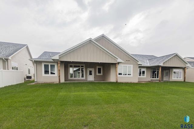 rear view of property with central air condition unit and a lawn