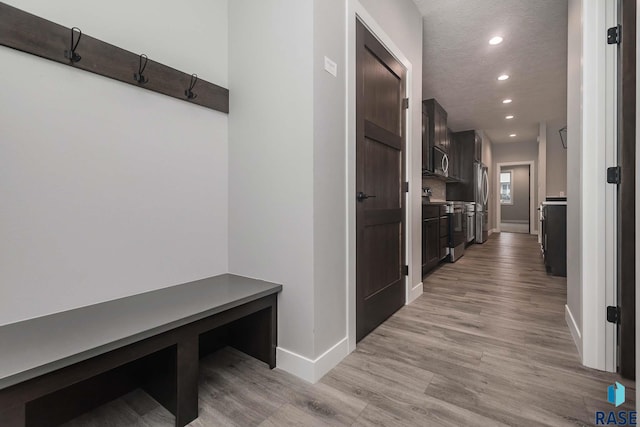 hallway with a textured ceiling and light hardwood / wood-style floors