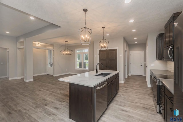 kitchen with sink, decorative light fixtures, a center island with sink, a notable chandelier, and stainless steel appliances