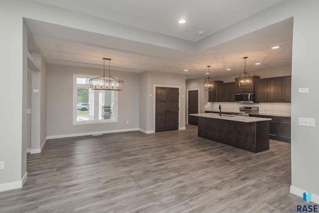 kitchen featuring sink, appliances with stainless steel finishes, tasteful backsplash, an island with sink, and decorative light fixtures