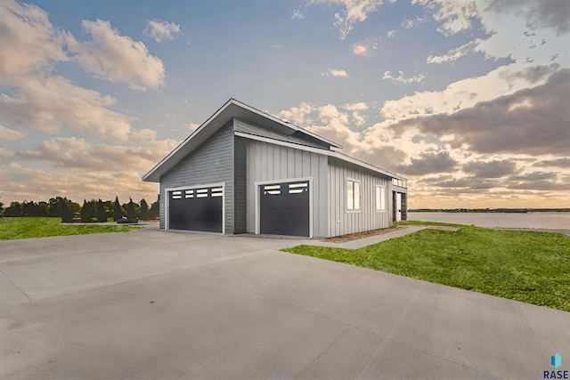 garage at dusk with a water view and a yard