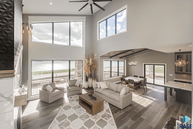 living room with a high ceiling, wood-type flooring, and ceiling fan with notable chandelier