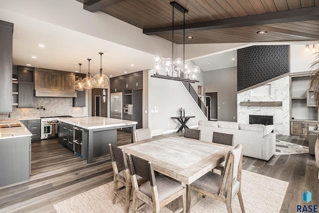 dining room featuring sink, wood ceiling, vaulted ceiling with beams, a fireplace, and dark hardwood / wood-style flooring