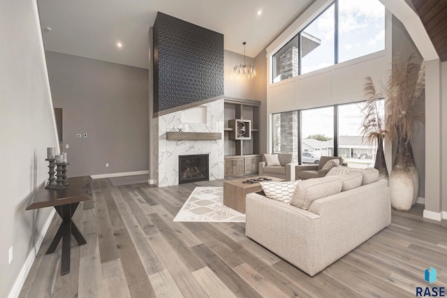 living room with hardwood / wood-style flooring, a towering ceiling, and a high end fireplace