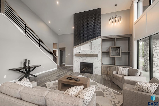 living room with a high ceiling, dark hardwood / wood-style floors, a chandelier, and a fireplace