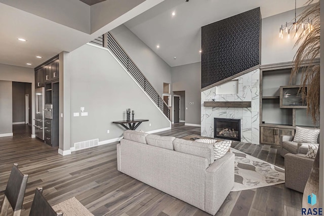 living room with a high ceiling, a fireplace, and dark hardwood / wood-style flooring