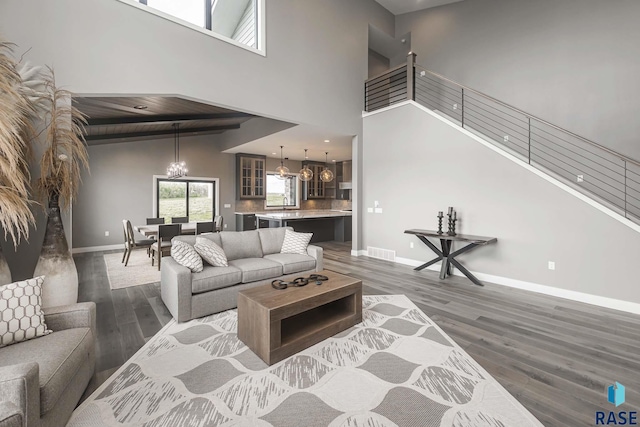 living room featuring an inviting chandelier, dark hardwood / wood-style floors, and a high ceiling