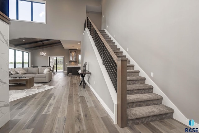 stairs featuring an inviting chandelier, a towering ceiling, and hardwood / wood-style floors