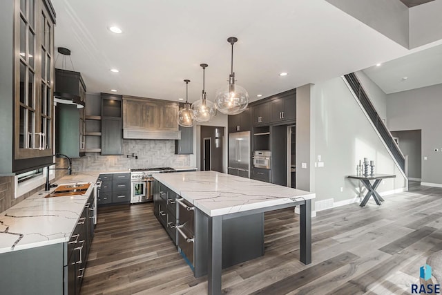 kitchen featuring a spacious island, decorative light fixtures, light stone countertops, and sink