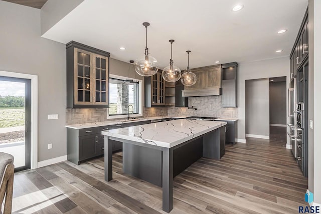 kitchen with pendant lighting, sink, a kitchen breakfast bar, decorative backsplash, and a center island