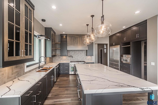 kitchen featuring hanging light fixtures, light stone countertops, sink, and a spacious island