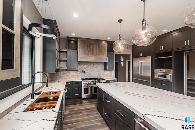 kitchen with tasteful backsplash, decorative light fixtures, light stone countertops, and high quality appliances