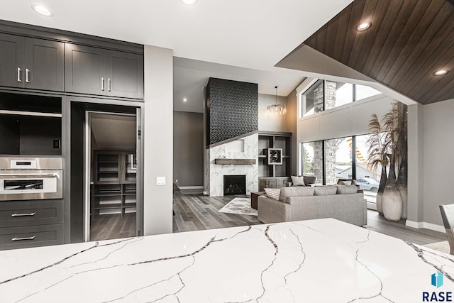 bedroom with stainless steel built in refrigerator, wood-type flooring, wooden ceiling, and a fireplace