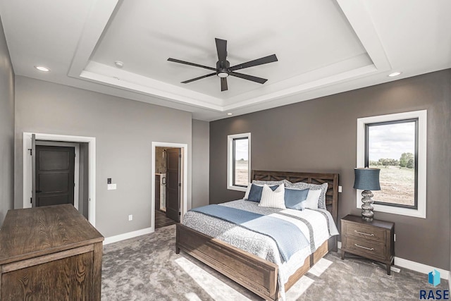 bedroom featuring a tray ceiling, carpet floors, and ensuite bathroom