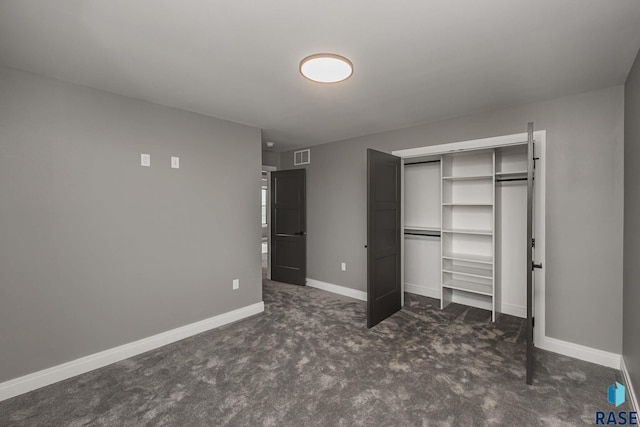 unfurnished bedroom featuring dark colored carpet and a closet