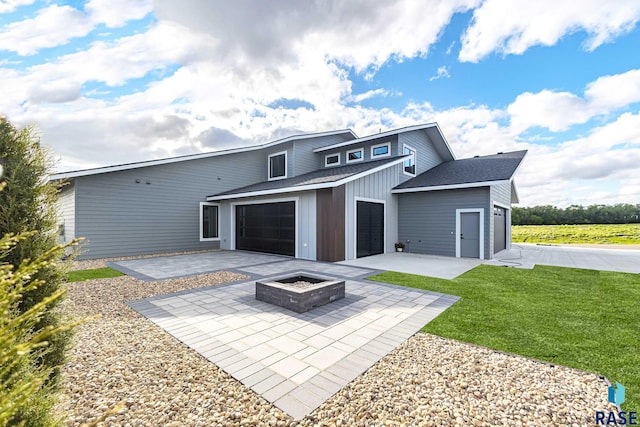 back of house with a garage, a patio, a yard, and an outdoor fire pit