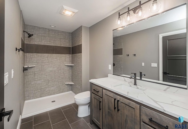 bathroom featuring vanity, tile patterned floors, toilet, and tiled shower