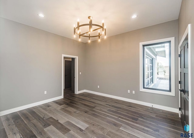 spare room featuring dark hardwood / wood-style floors and a notable chandelier