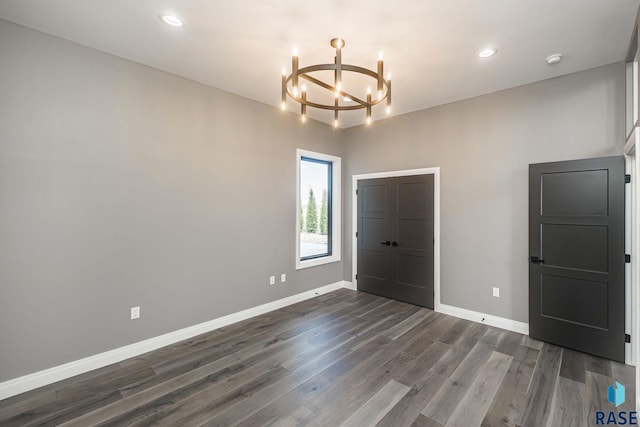 unfurnished bedroom with dark hardwood / wood-style flooring and a chandelier