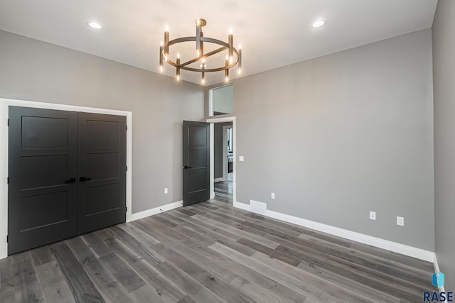 unfurnished bedroom featuring wood-type flooring and a notable chandelier