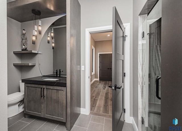 bathroom featuring vanity, tile patterned flooring, a shower with shower door, and toilet