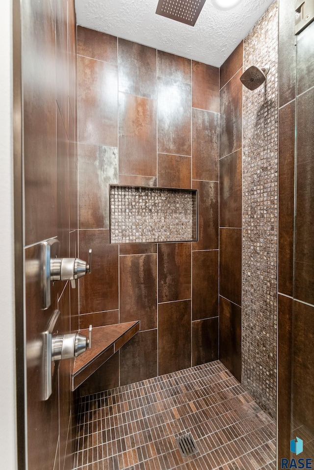 bathroom with tiled shower and a textured ceiling