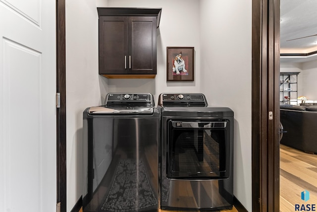 laundry room with hardwood / wood-style flooring, washing machine and dryer, and cabinets