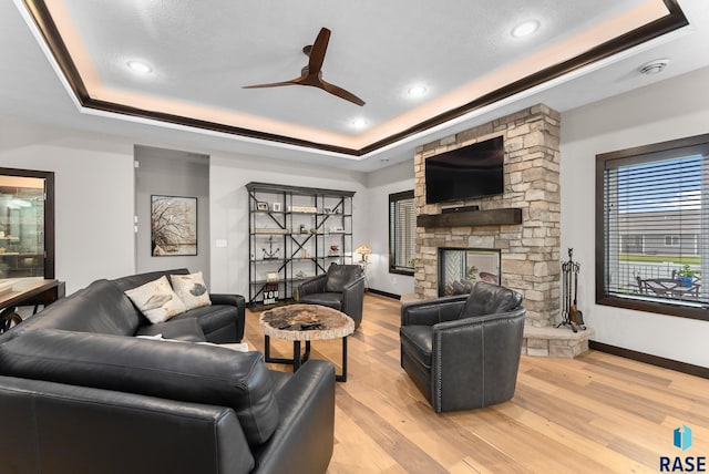 living room featuring a fireplace, a raised ceiling, and light hardwood / wood-style flooring