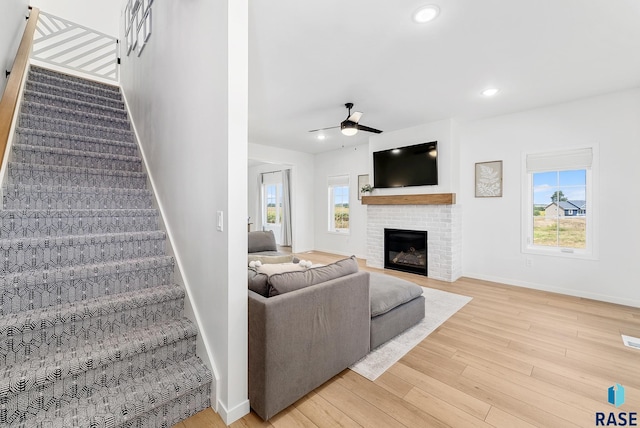 living room featuring ceiling fan, wood-type flooring, and a fireplace