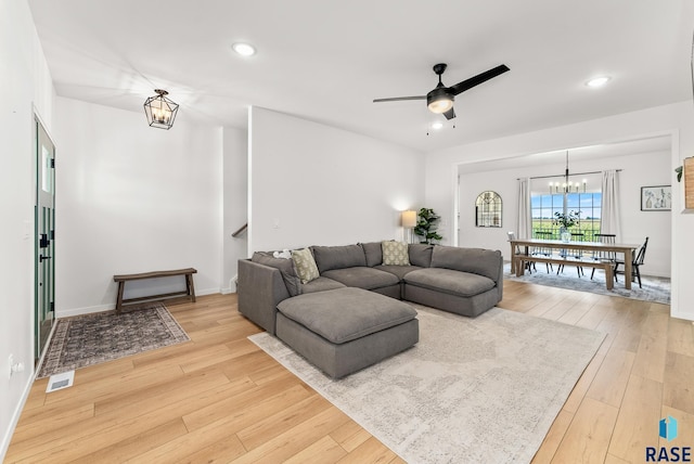 living room featuring ceiling fan with notable chandelier and wood-type flooring