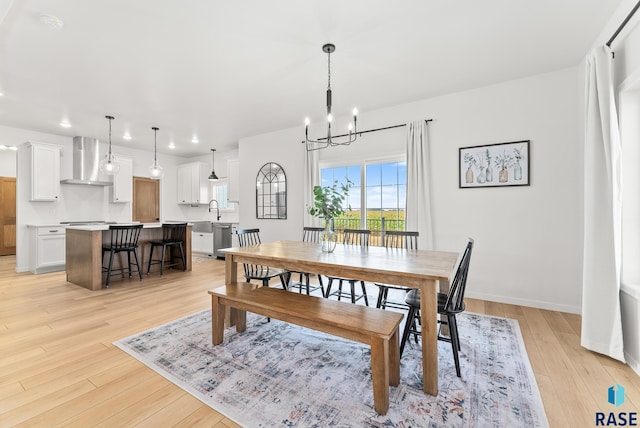 dining area featuring sink, a chandelier, and light hardwood / wood-style flooring