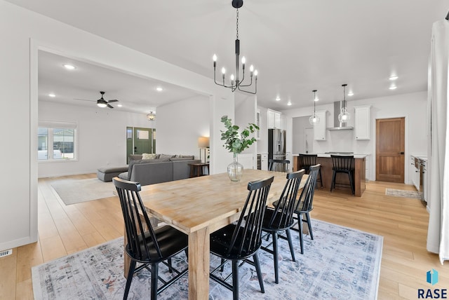 dining area featuring ceiling fan with notable chandelier and light wood-type flooring