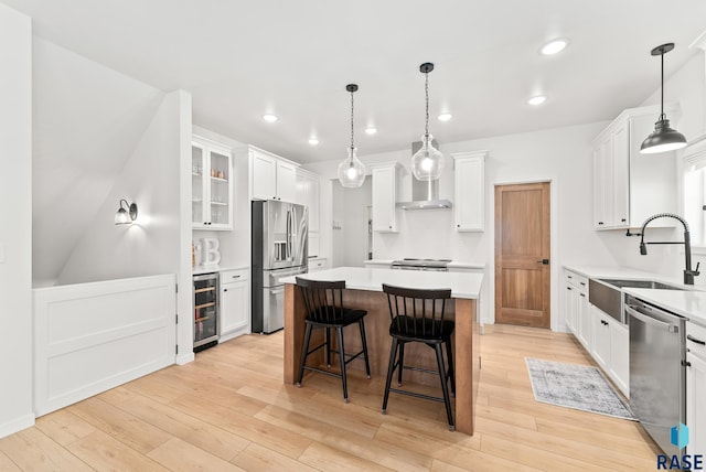 kitchen with sink, a kitchen island, pendant lighting, stainless steel appliances, and white cabinets