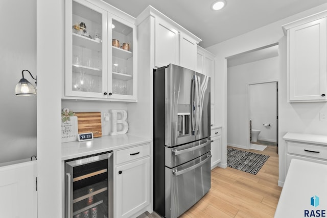 kitchen with stainless steel refrigerator with ice dispenser, white cabinetry, light wood-type flooring, and wine cooler